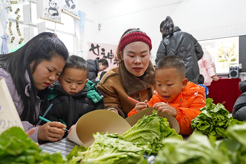 2025年3月6日，贵州省毕节市纳雍县龙场镇中心幼儿园“温情三八·感恩有您”活动现场，家长和孩子们一起做手工。 杨 英 摄