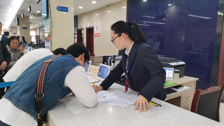 政务服务现场，工作人员指导群众填资料（苏布祥 摄）.jpg
