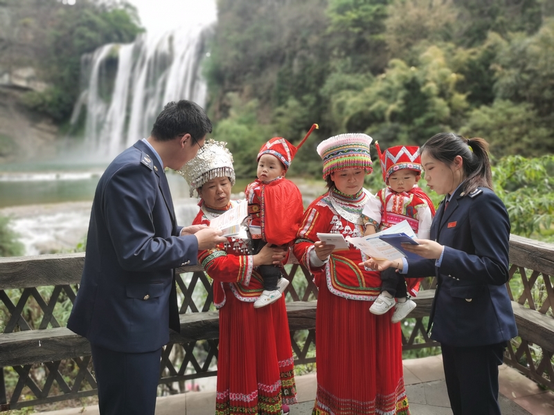 黄果树大瀑布景区，安顺市镇宁县税务局干部正在为少数民族纳税人讲解政策。舒开培摄