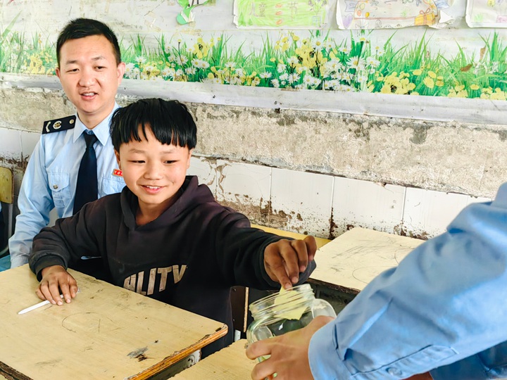 学生将写在小纸条上对未来公平发展的期待，放入“税法心愿瓶”中。陶圣洁摄