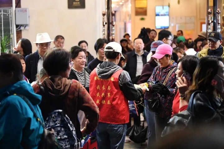 3 社区志愿者正在为出行的游客发放一次性雨衣.jpg