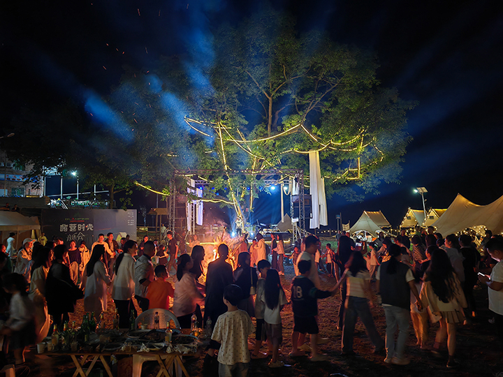 4、游客夜晚围坐篝火旁，品尝烧烤、仰望星空，沉浸于“时光音乐会”的民谣弹唱中。王琨荣摄