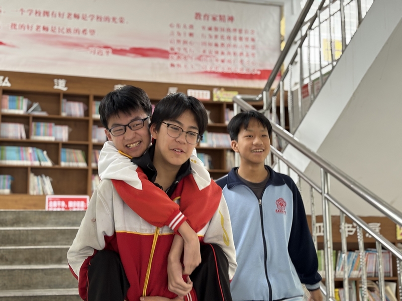 陈璟天背着方证淇走在路上，罗顺洋陪在一旁。肖年童摄