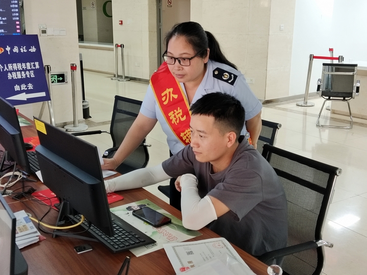 税务工作人员在自助办税区辅导纳税人使用电子税务局办理业务。