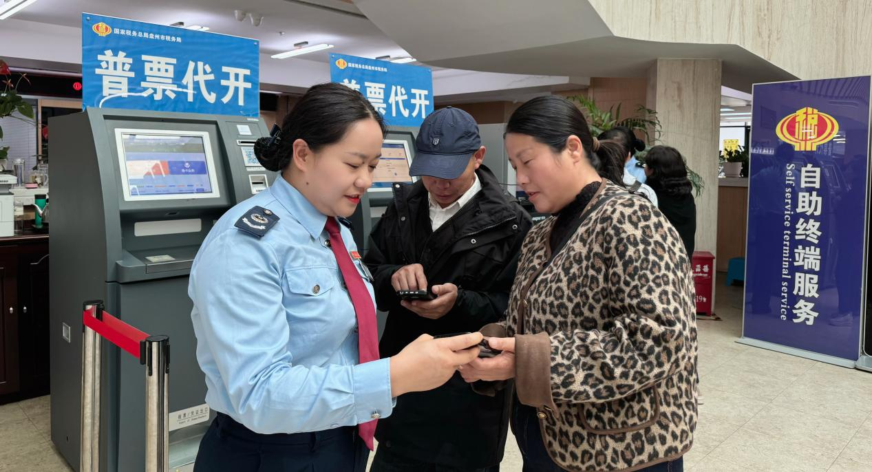 图为 税务干部辅导纳税人使用电子税务局APP开具发票 张玉英/摄