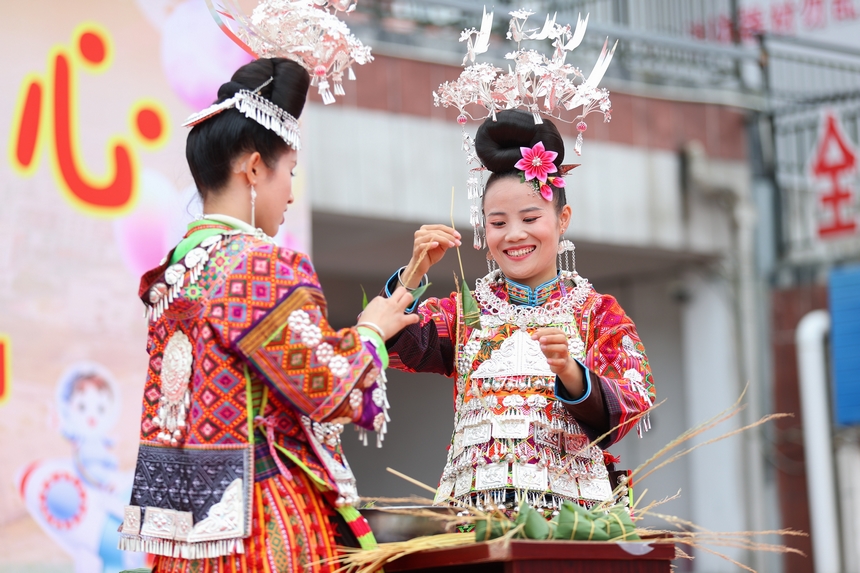 2025年5月29日，在贵州省丹寨县金泉街道，身着传统服饰的搬迁群众在参加包粽子比赛。