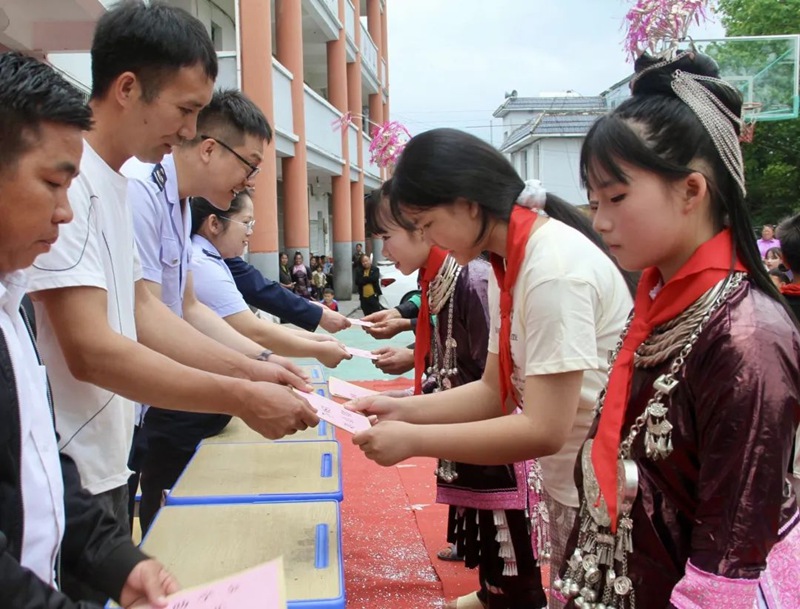 稅務干部向祥心村學生代表發放助學金和學習用品。