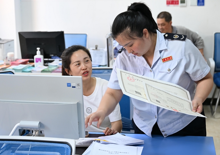 在自助办税区，税务人员辅导纳税人自助办理涉税业务.jpg