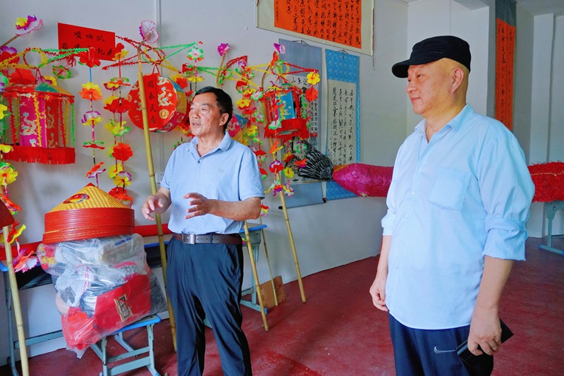 赵军（右）和老年学校名誉校长覃礼富在展陈室介绍老年学校情况。