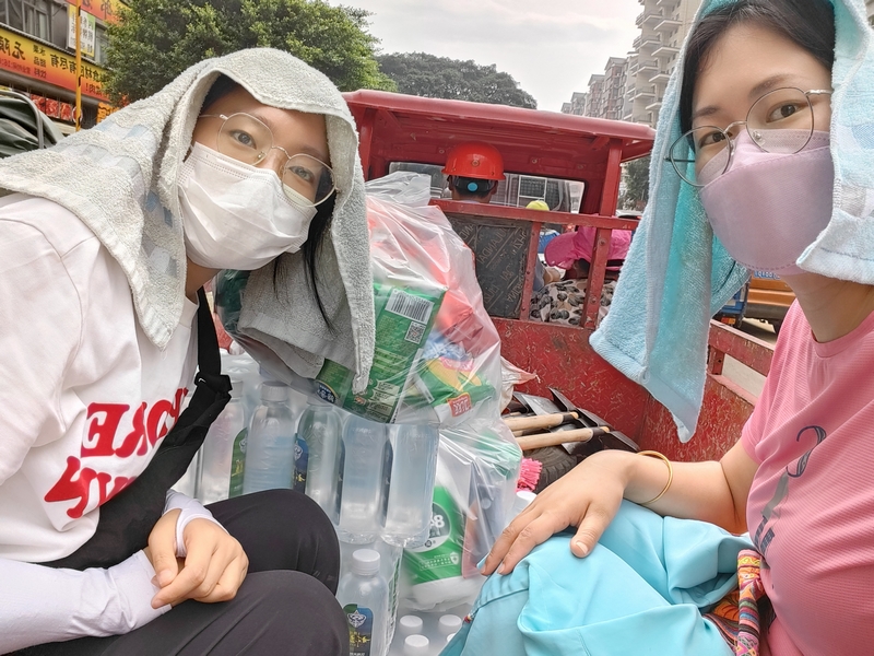 榕江县税务局党员干部袁剑欣和蒋光慧利用三轮车将郊区购买的应急物资运送到单位。