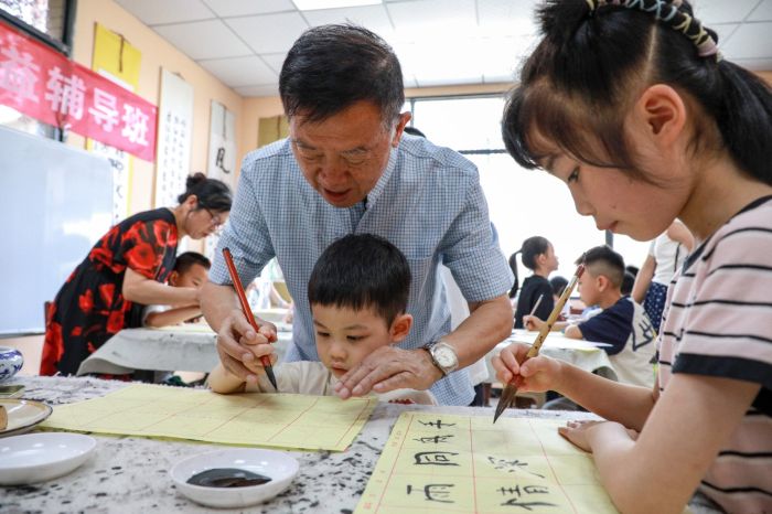银龄老师罗用能耐心教孩子们书写毛笔字.jpg
