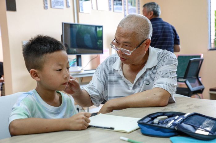 银龄老师周双林纠正孩子的硬笔书写姿势.jpg