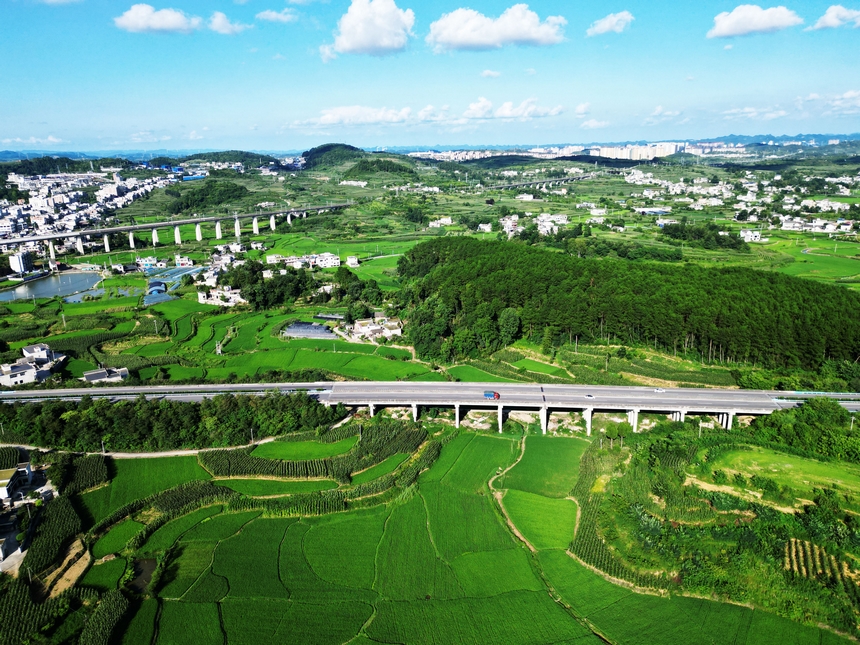 2025年7月20日，夏日的贵州省黔西市林泉镇合心村，高速公路与田园、村居、远山相映成景，乡村如画。 