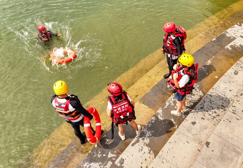 消防员在指导小朋友体验救生圈救援。
