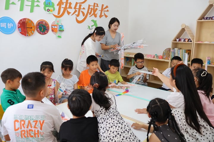 在花秋鎮花秋社區“兒童之家”，老師正在給學生們發風箏 （王洪婭攝）.JPG