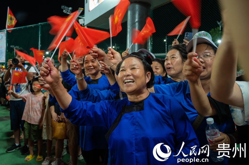观众挥舞着红旗为巡游队伍喝彩。人民网 阳茜摄