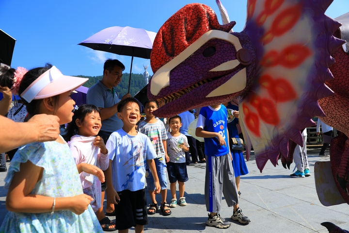 8月1日，贵州省剑河县校场坝，小朋友们在和恐龙化石人偶互动。杨家孟 摄  (2).JPG
