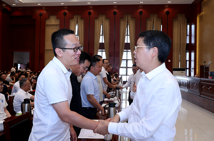 清鎮市半年經濟工作會議會上，馬驍、吳永康等領導與企業家一一握手。