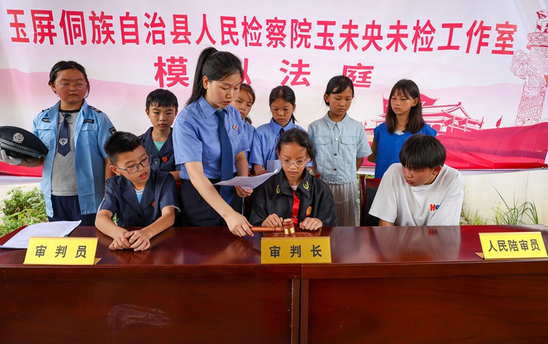 检察干警志愿者在指导小朋友体验“模拟法庭”。