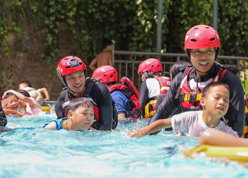 消防員指導學生進行溺水自救實操。