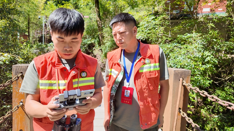 吴攀胜(左)认真的操作无人机。税会静摄