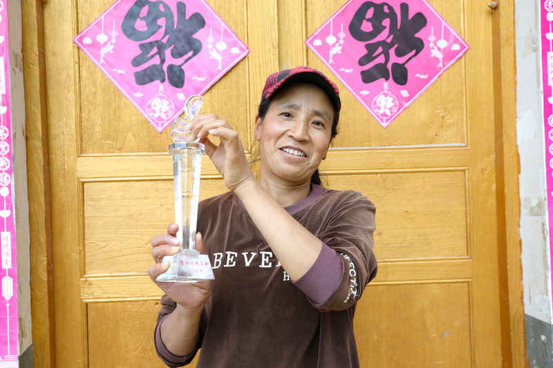 青松村村民吴长芬向记者展示获得的“好儿媳”奖杯。廖槐花摄