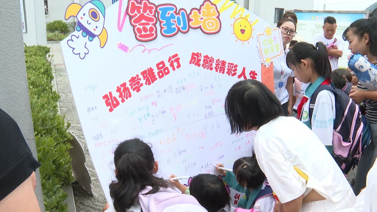 县第七小学学生在签到墙上写下自己的名字。