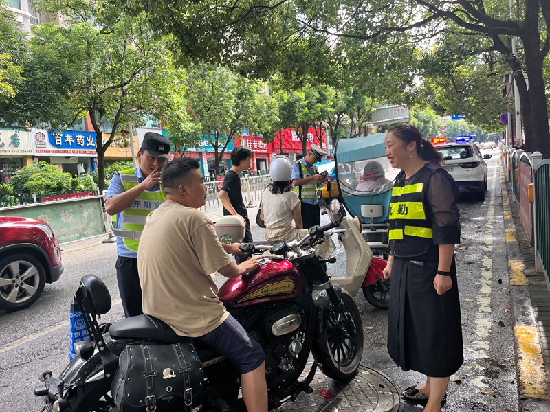 工作人员与民警将未戴头盔的车主拦截.jpg
