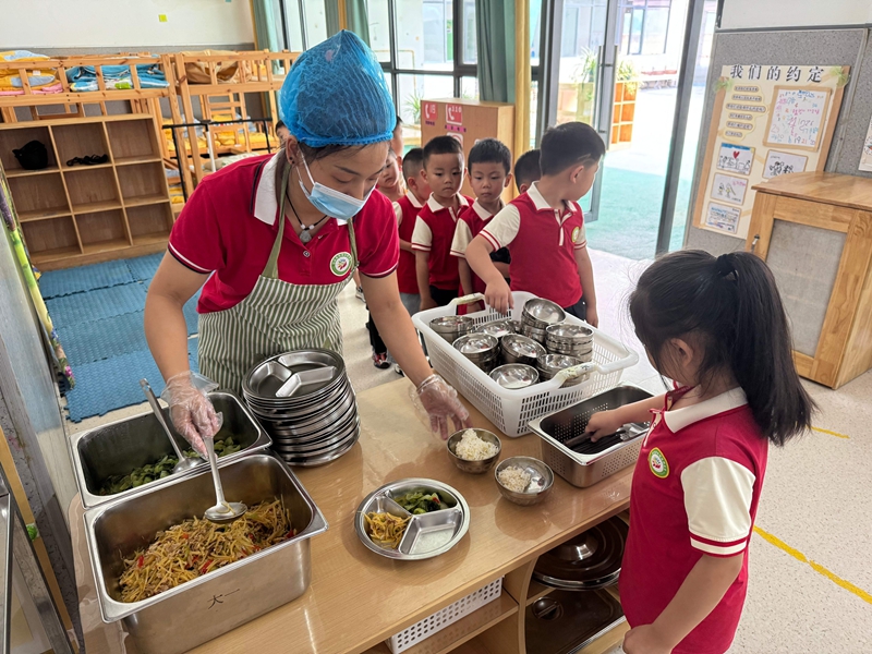 幼儿园工作人员为孩子们分餐，餐食丰富多样。谢永恒  摄.jpg