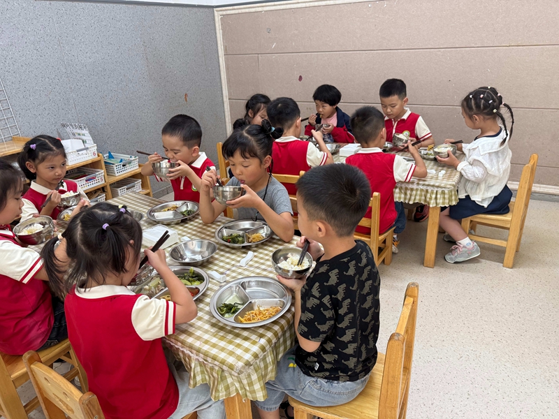 幼儿园孩子们在餐桌前开心用餐，氛围温馨。谢永恒  摄.jpg