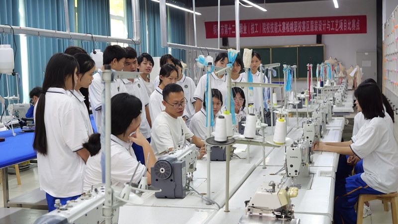 服装设计与工艺专业学生在观摩教师缝纫机的基础操作。.jpg