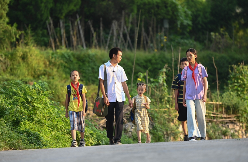 松桃苗族自治县迓驾镇教师任达兵带着学生走在上学路上。谢慧芳摄 (2).JPG