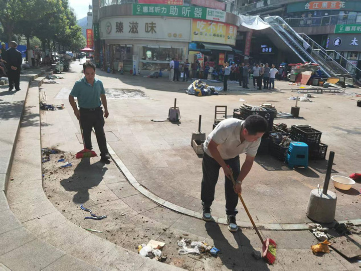 图为摊贩搬移后,附近居民主动上前打扫卫生。