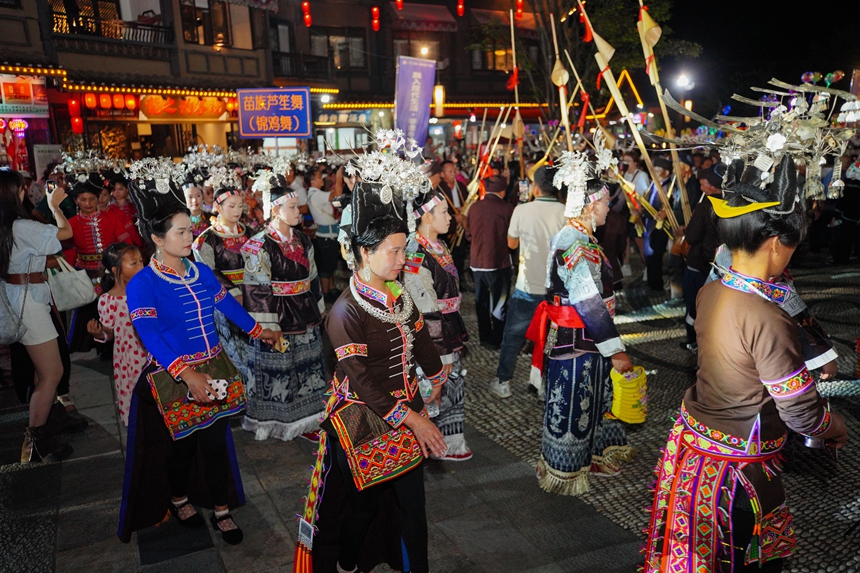 9月16日，在贵州省丹寨县万达小镇，身着传统服饰的苗族群众与游客在跳芦笙舞。