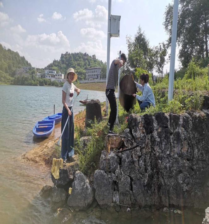 苏流芳与驻村工作队在湖面上清理垃圾。