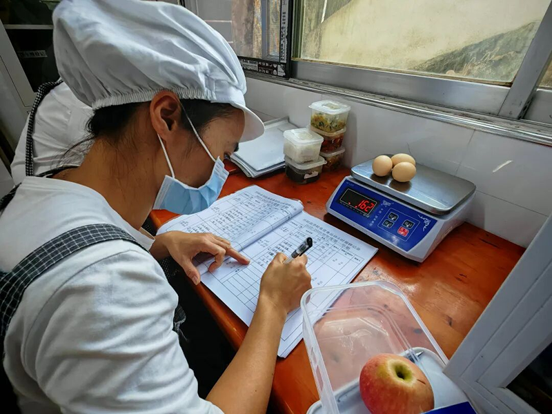食堂工作人员对当日午餐进行取样、留样记录.