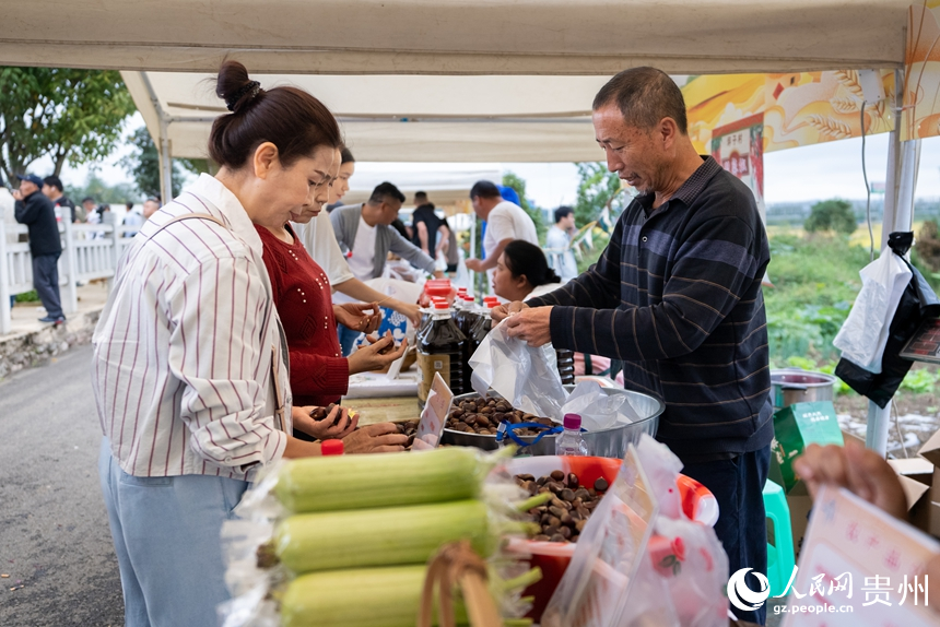参加活动的观众在农特产品展示区内购买农特产。人民网记者 涂敏摄