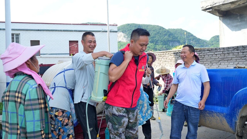 2 图为皮庆柏（右二）背上农药桶与村民一起喷洒农药.jpg