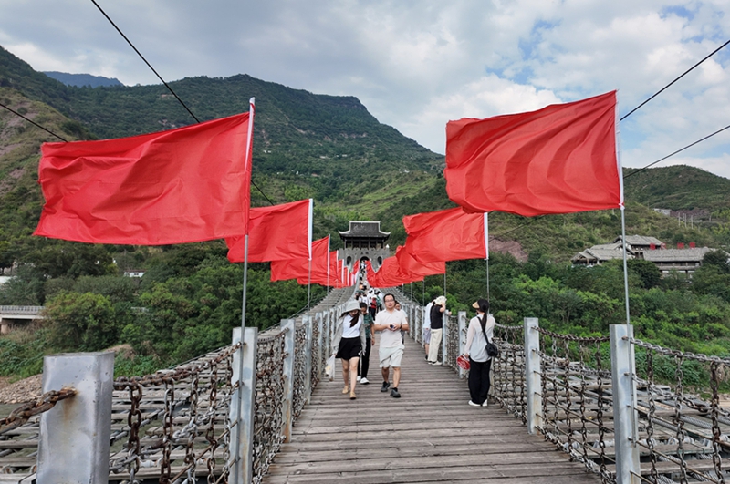 鐵索橋上一排排整齊懸挂的紅旗迎風招展。姚瑤 攝.jpg