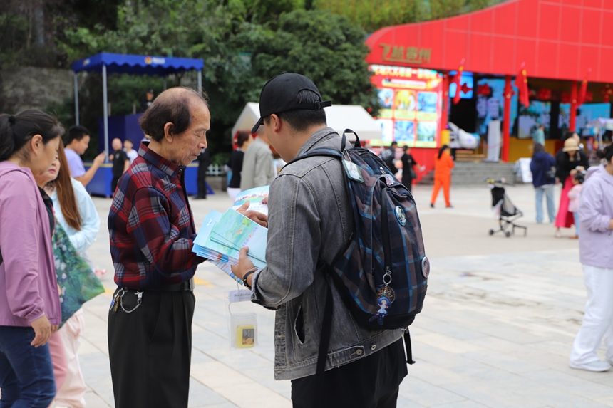 云岩区文体广电旅游局工作人员正将《旅游安全实务手册》递到游客手中，准备进行详细讲解。