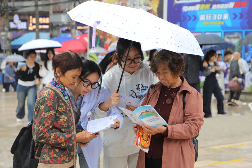 科普现场，学生志愿者正结合《旅游避“坑”指南》，为游客详细解析常见旅游消费陷阱。