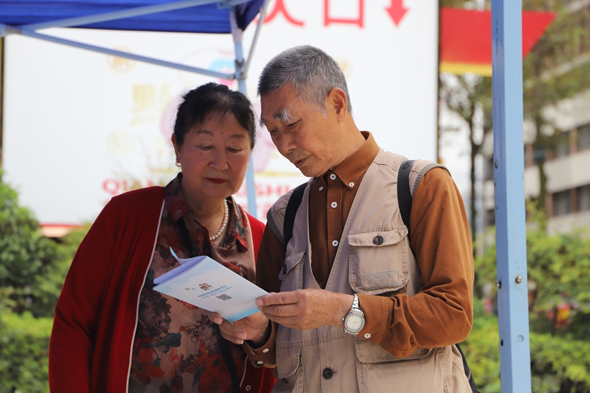 两名游客正在认真阅读《旅游安全实务手册》。