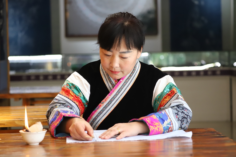 织金县蔡群苗族蜡染刺绣有限公司总经理蔡群用蜡刀在画布上勾勒图案（孙继霞 摄）