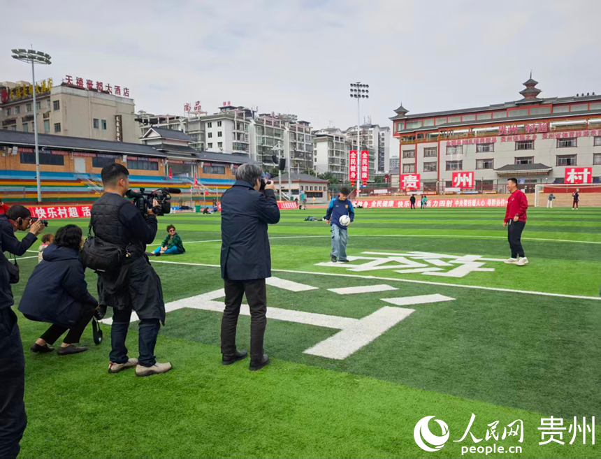 媒体团走进贵州榕江“村超”球场，与“村超”球员交谈、踢球。人民网 龙章榆摄