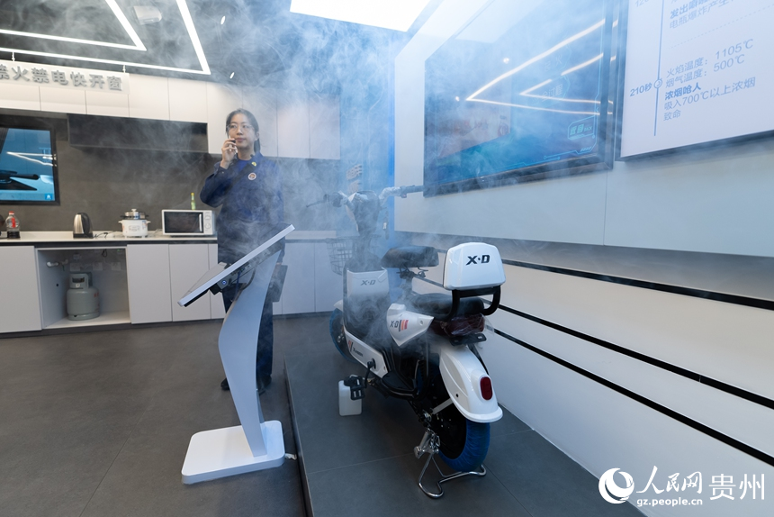 讲解员为参观者演示电动车充电起火燃烧过程。人民网记者 涂敏摄