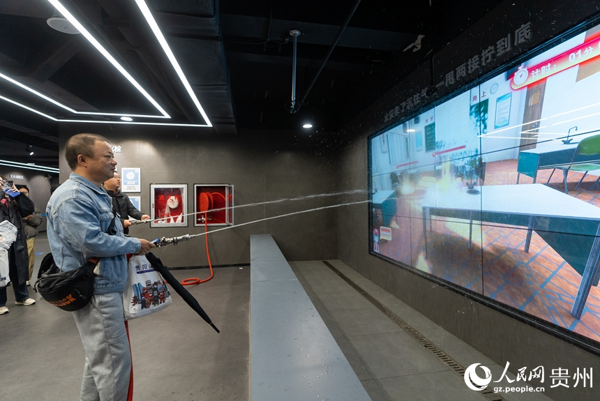 参观者在科普教育馆内体验消防水枪灭火。人民网记者 涂敏摄