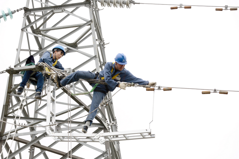 nEO_IMG_南方电网贵州兴义供电局输电管理所综合数据班高级作业员龙福刚带领徒弟应用自己研发的安全工具器在110千伏高压输电线路上开展检修工作。卢关文摄