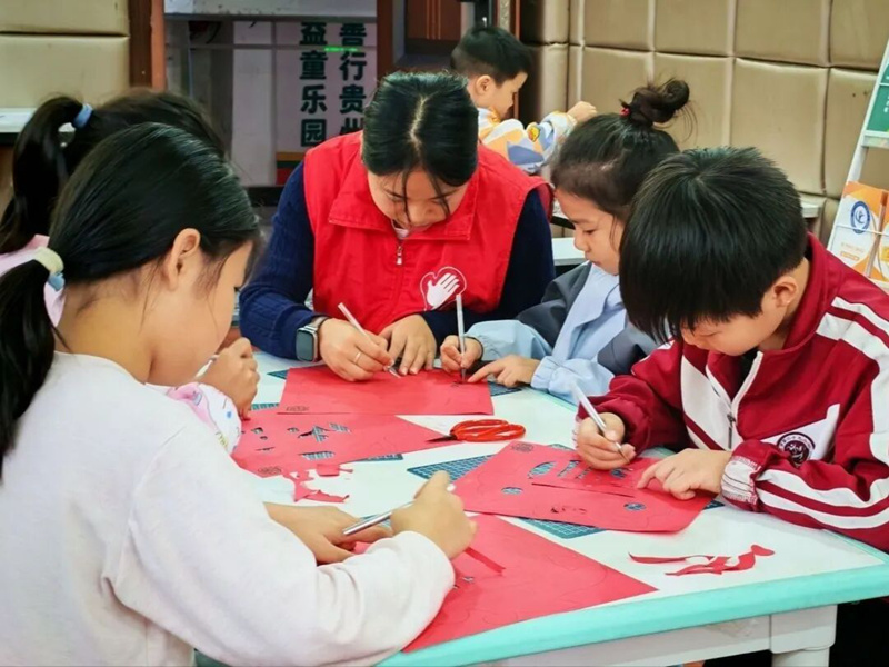 丹都街道旺家社區的志願者和社區孩子們一起進行剪紙創作。