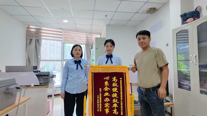 贵州添禧装饰工程有限公司法人将锦旗送到金沙县住建局派驻窗口首席代表手中 胡凤至 摄.jpg