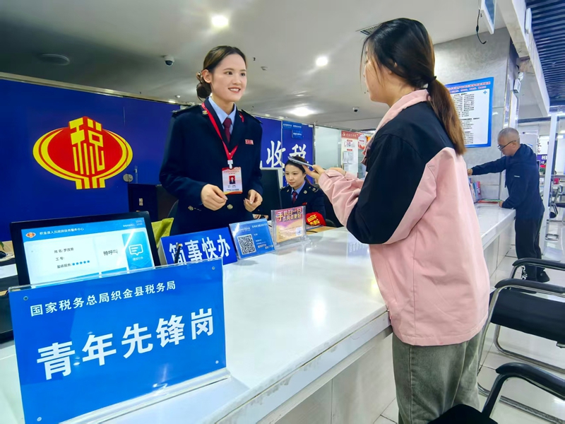 图为税务干部为纳税人办结税务事项并讲解相关税费优惠政策。童霖摄